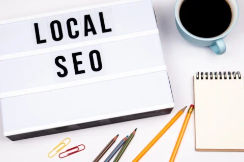 Top view of a workspace with a lightbox showing the words 'Local SEO', pencils, notebook, and a cup of coffee. Ideal for blog posts about local search engine optimization strategies.